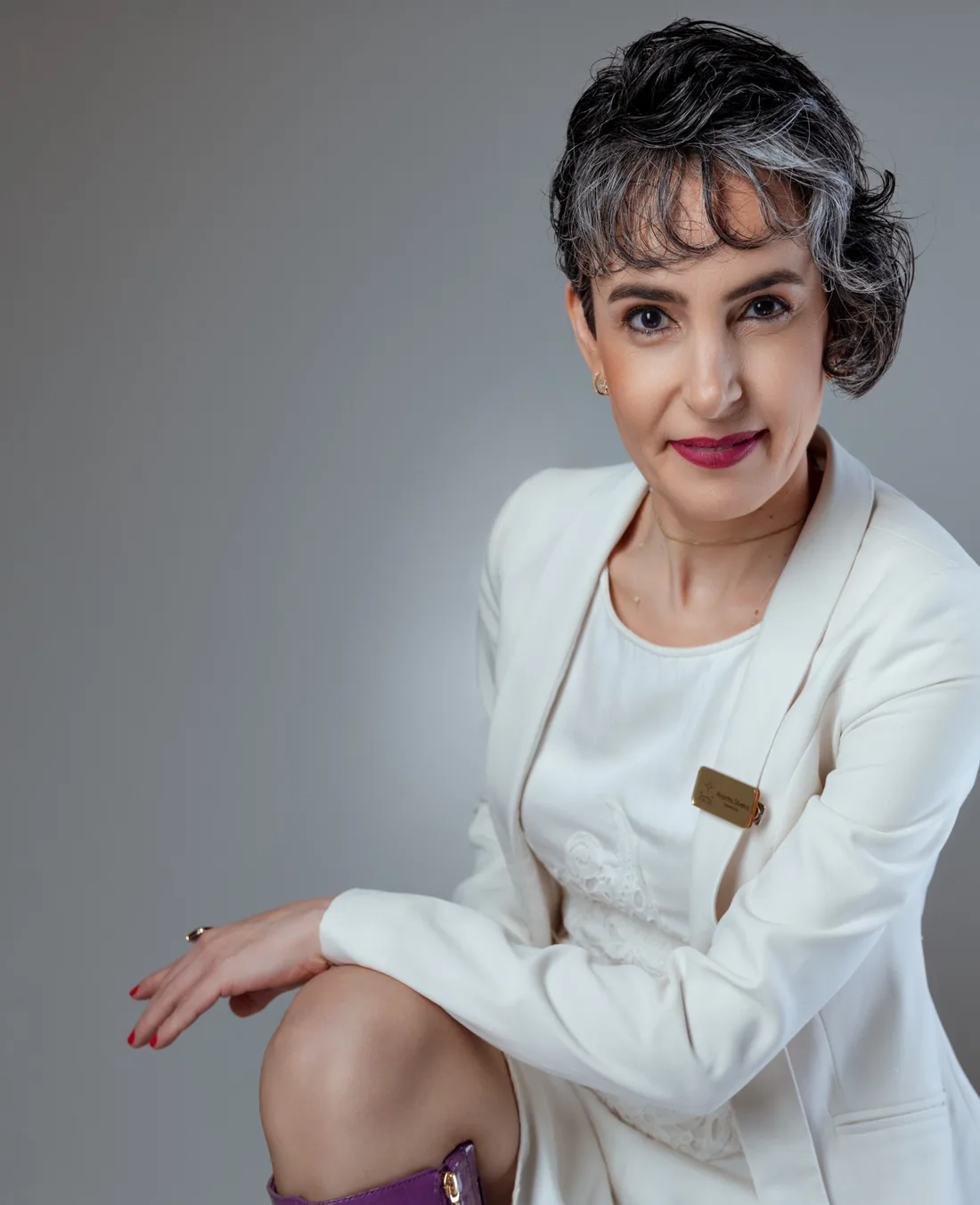 Anaritta Silveira, terapeuta integrativa, sentada, de blazer branco